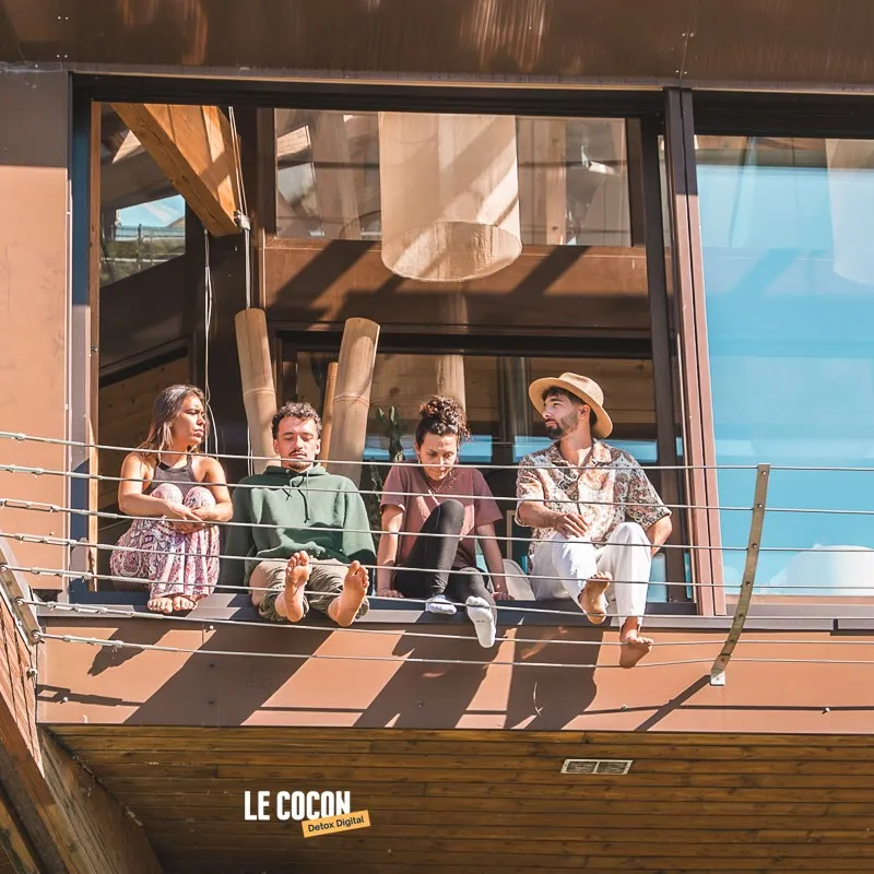 Participants détendus sur la terrasse en bois au soleil lors d'une retraite Le Cocon